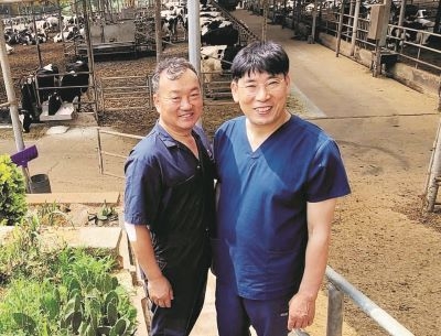 장우목장 한길우(왼쪽)·권순균 공동대표가 바쁜 일손을 멈추고 우사를 배경으로 포즈를 잡았다.